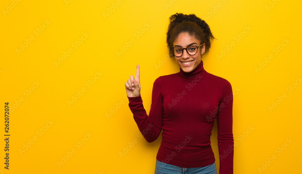 Young black african american girl with blue eyes showing number one Young black african american girl with blue eyes showing number one