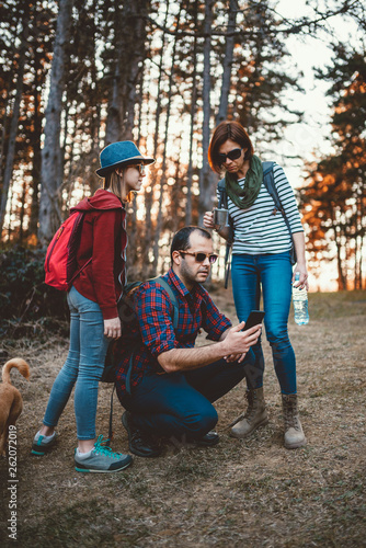 Family hiking in the forest and using smart phone