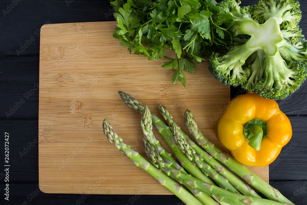 Vegetables on the brown cutting board on the black wooden background.Top view.Copy space.Healthy food. Vegetables on the brown cutting board on the black wooden background.Top view.Copy space.Healthy food.