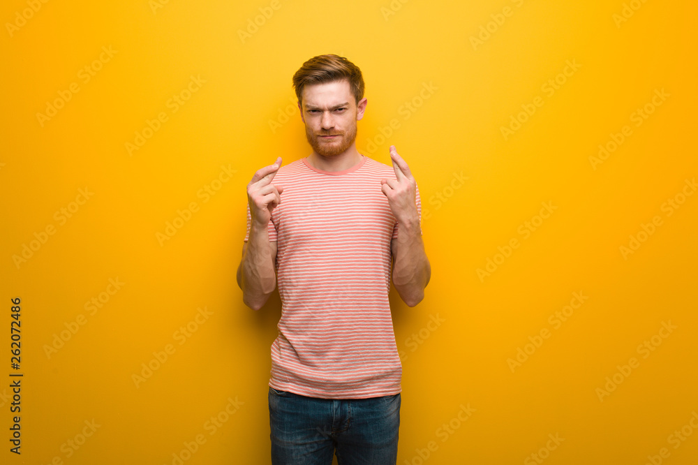 Young redhead man crossing fingers for having luck Young redhead man crossing fingers for having luck