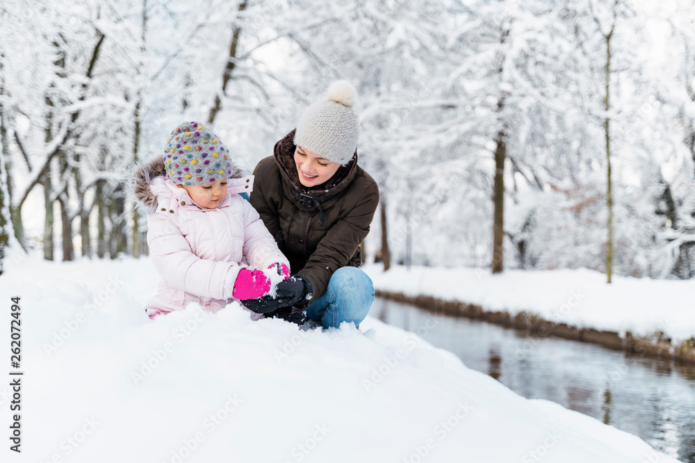 Happy mother with daughter at a moat in winter landscape Happy mother with daughter at a moat in winter landscape