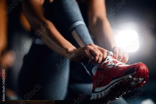 Close up of female athlete tying shoelace before the workout.