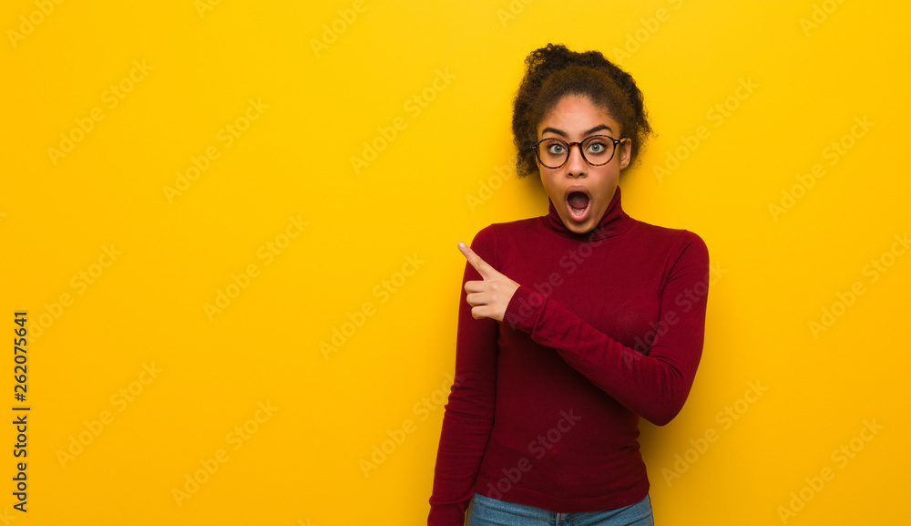 Young black african american girl with blue eyes pointing to the side Young black african american girl with blue eyes pointing to the side