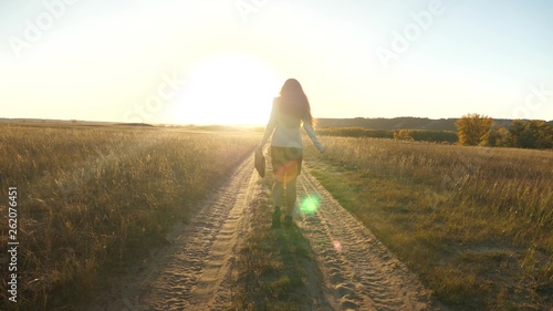 business woman walking along country road with a briefcase in her hand. sexy business woman girl working in rural area. woman farmer inspects land at sunset. agricultural business concept.