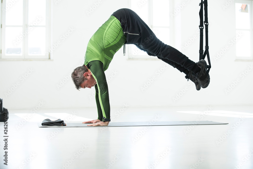 Man doing his fitness regime, doing suspension training Man doing his fitness regime, doing suspension training