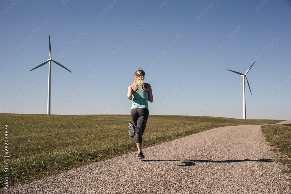 custom made wallpaper toronto digitalYoung woman jogging on field way, wind wheels in the background