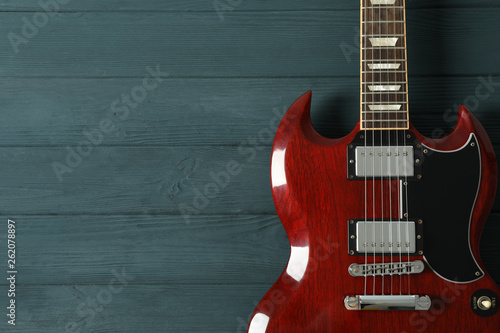 Beautiful six - string electric guitar on wooden background, space for text