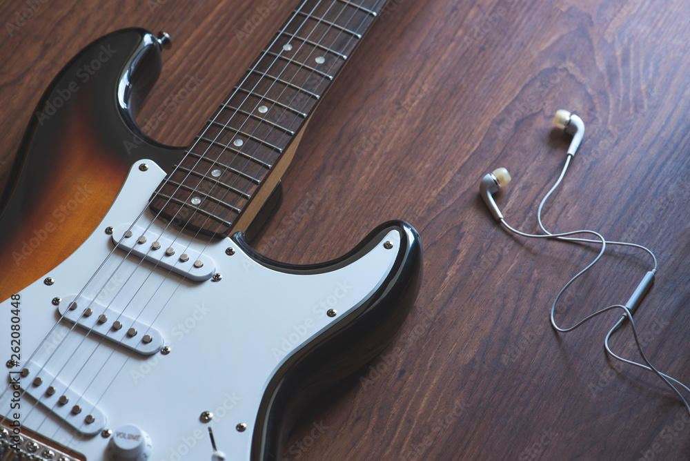 Fototapeta premium Electric guitar, headphones on the wooden background,