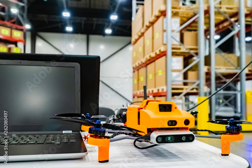 Office drone with a laptop. Warehouse equipment. Storage. Warehouse management. Drone inventory warehouse. Audit in stock. Scanning goods. Dron scans product information on the shelves.
