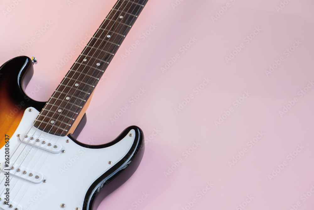 Obraz premium Electric guitar, headphones on the pink background.
