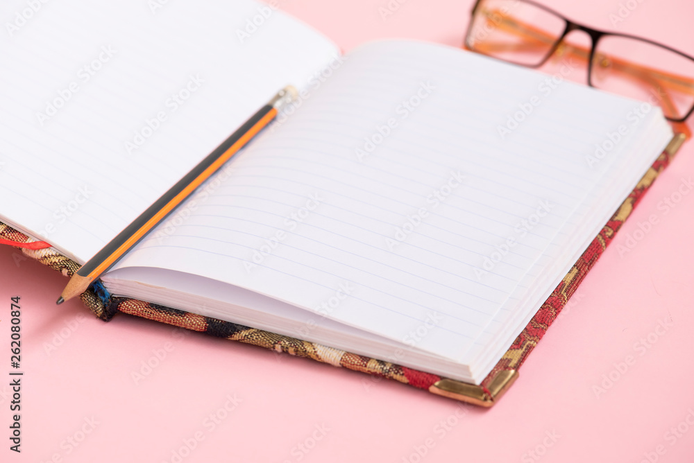 Notebook, panicle and glasses on the pink background. Notebook, panicle and glasses on the pink background.