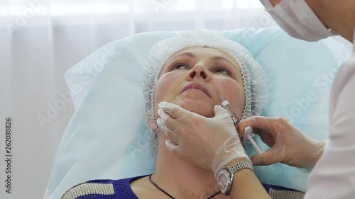 Close-up of hands of cosmetologist making botox injection in female lips. Portrait of young caucasian woman getting cosmetic injection of botox.