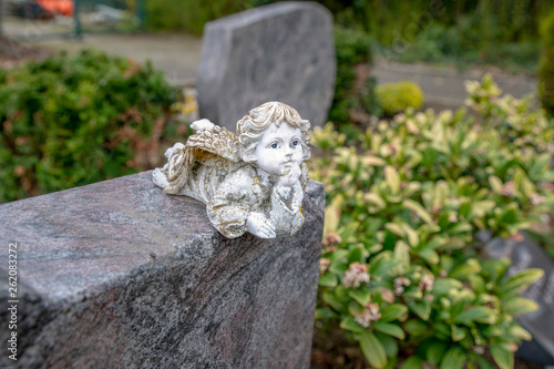 kleiner Engel liegt auf einem Grabstein