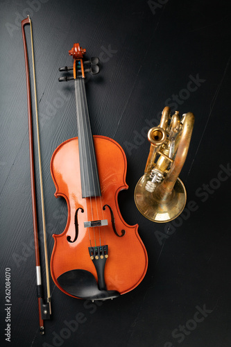 A new shining violin and an old trumpet on a dark table. Musical instruments  stringed and wind.