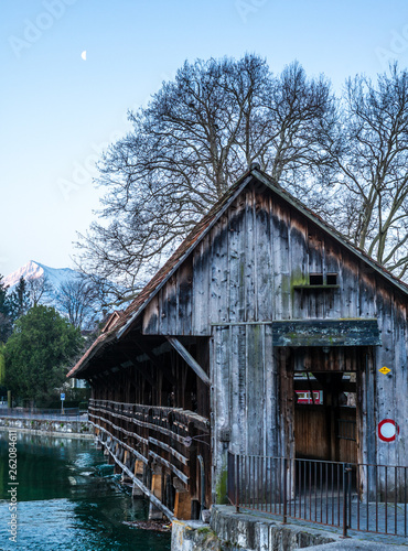 A wooden bridge crossing the river Aare in Thun with the Jungfrau and Eiger mountains in the background early in the morning - 2 © gdefilip