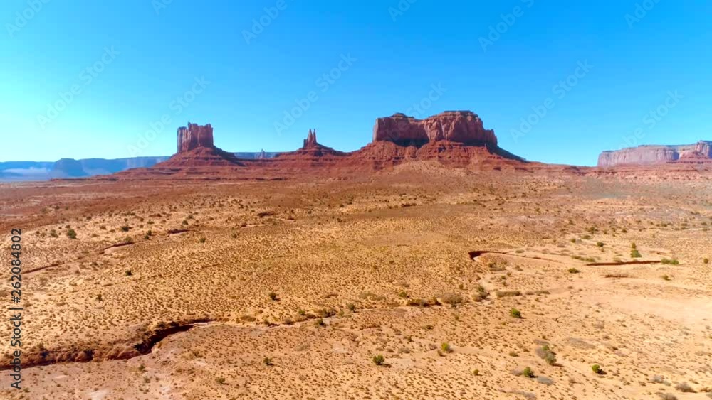 4K drone zoom in view of the Monument Valley and surrounding areas. The area of free standing sandstone rock forms that rise from the desert ground. 4K drone zoom in view of the Monument Valley and surrounding areas. The area of free standing sandstone rock forms that rise from the desert ground.