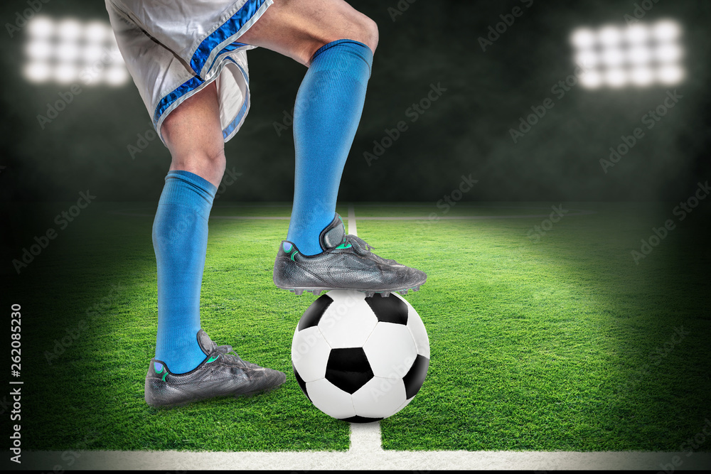 Spotlight on Soccer Player Standing Over Football in Outdoor Stadium With Copy Space