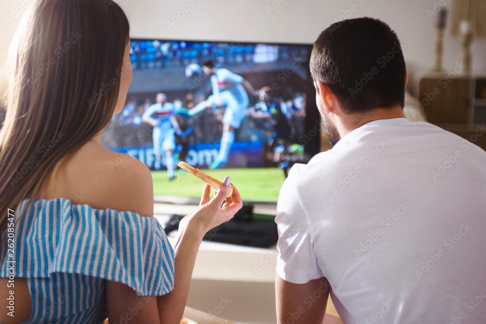 Young lovely couple watching football soccer game on tv at home together Young lovely couple watching football soccer game on tv at home together