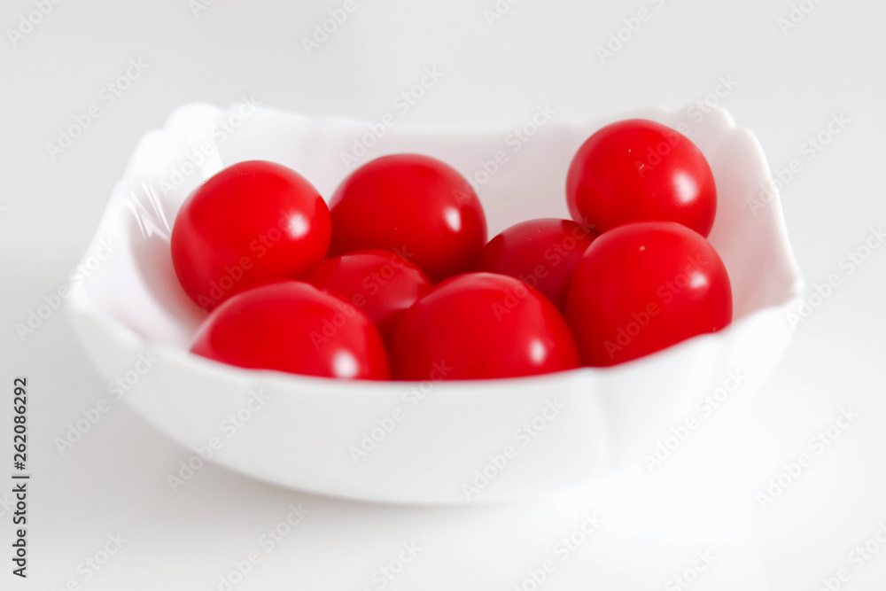 Fresh cherry tomatoes in a white plate, on a white background, White and Red Concept Fresh cherry tomatoes in a white plate, on a white background, White and Red Concept