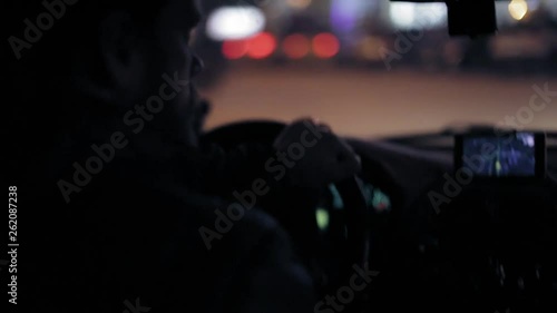 A man gets into the car and turns on the navigator on the smartphone