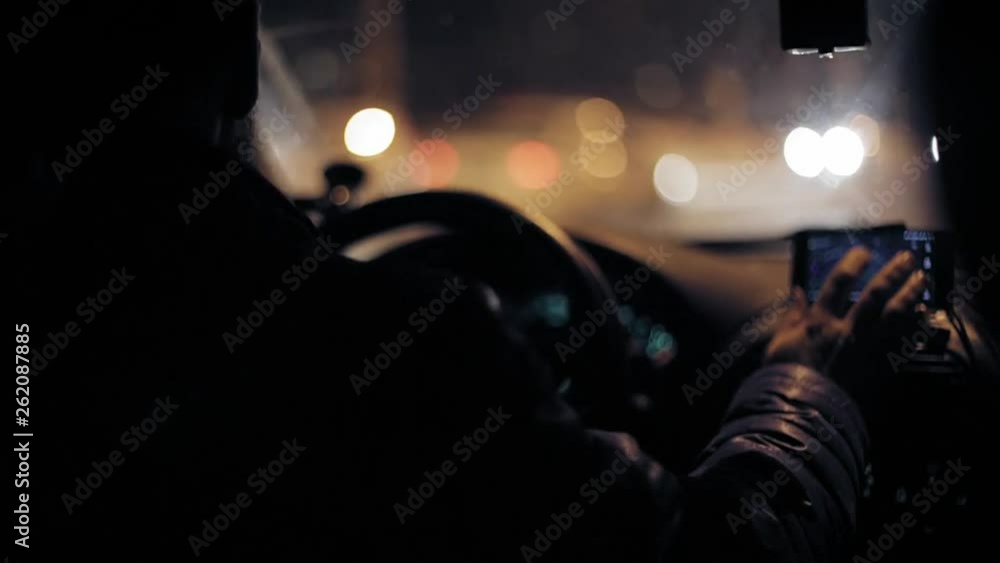 A man gets into the car and turns on the navigator on the smartphone A man gets into the car and turns on the navigator on the smartphone