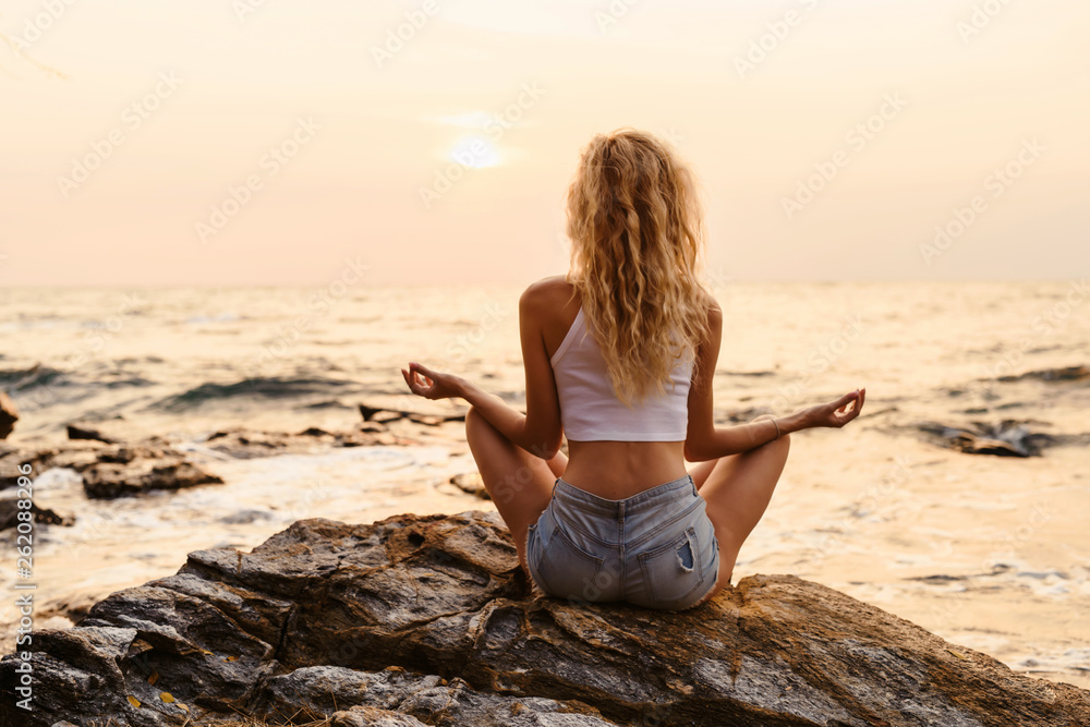 Young woman practicing yoga at the beach sea view at sunrise or sunset outdoors. Harmony and meditation concept. Healthy lifestyle Young woman practicing yoga at the beach sea view at sunrise or sunset outdoors. Harmony and meditation concept. Healthy lifestyle