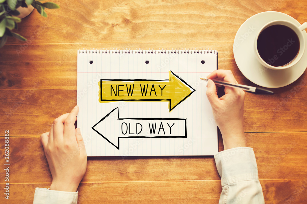 Old way or new way with a person holding a pen on a wooden desk Old way or new way with a person holding a pen on a wooden desk