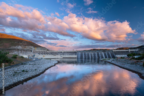 Grand Coulee Dam in central Washington State under a colorful sunset. The dam is the largest capacity power station in the U.S.  The nearby Franklin Delano Roosevelt Reservoir provides water for the irrigation of 670,000 acres of farmland in the Columbia Basin. 3,000 people were forced to relocate before construction and numerous First Nation ancestral land sites were flooded. The monumental project was one of a variety of FDR era New Deal projects. photo