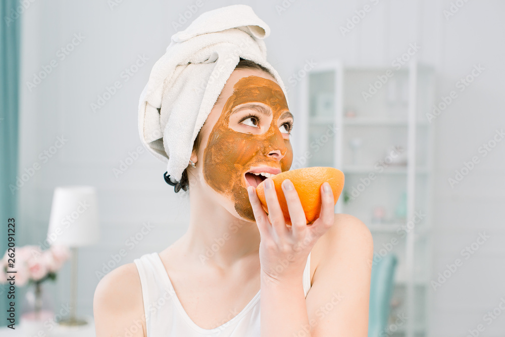 portrait of pretty young woman with clay mask on her face holding slices of lemon and grapefruit, facial care portrait of pretty young woman with clay mask on her face holding slices of lemon and grapefruit, facial care