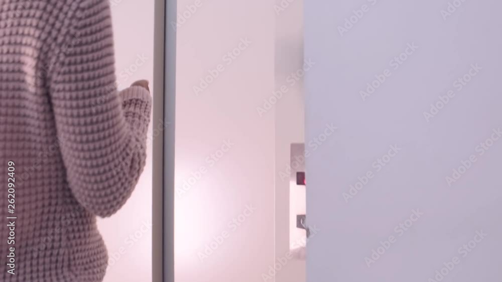 Young confident woman enters elevator, pushes button, door closes. She is using smartphone mobile office app. Young confident woman enters elevator, pushes button, door closes. She is using smartphone mobile office app.