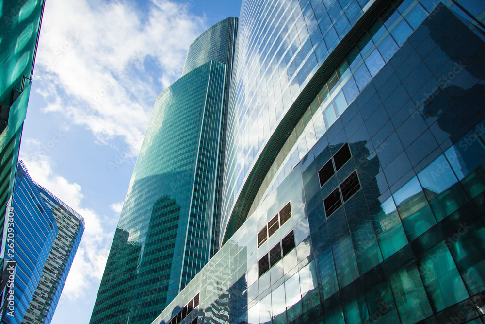 Business concept of future architecture, panoramic looking up to top of building. View of high rise glass building and window system on blue sky background.