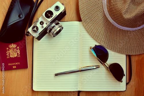 Retro camera, hat, passport notebook and pen, all of them over a  on wooden table - travel concept