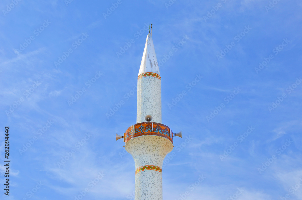Amazing close up view of the white minaret tower taken from below against the blue sky. The beautiful minaret is part of the islamic mosque in Dipkarpaz, Karpas Peninsula, Northern Cyprus. Amazing close up view of the white minaret tower taken from below against the blue sky. The beautiful minaret is part of the islamic mosque in Dipkarpaz, Karpas Peninsula, Northern Cyprus.