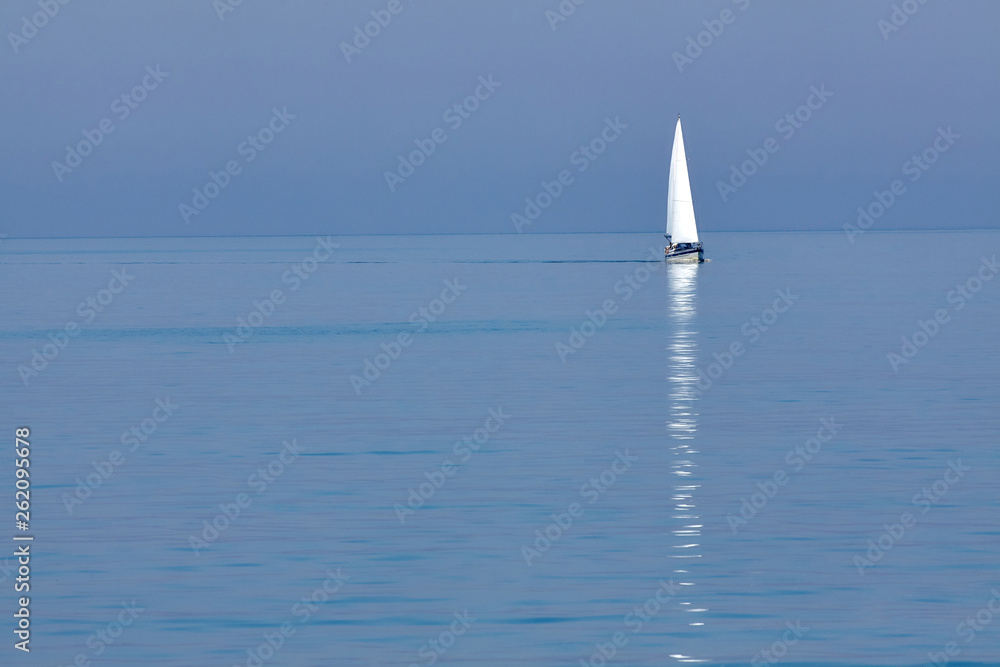 White sailing yacht in the blue sea on the horizon. Seascape. Minimalism.