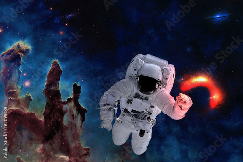 Fototapeta Naklejka Na Ścianę i Meble -  Space astronaut near black hole glow near pillars of creation. Space adventure in outer space. Science fiction. Elements of this image were furnished by NASA