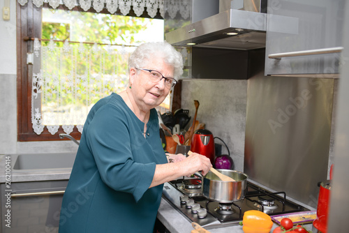 Fotografie happy senior active woman cooking at home in a modern kitchen