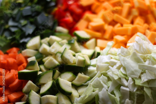 Various chopped vegetables: butternut squash, cabbage, red pepper, courgette, leek and carrot. Top view, selective focus.