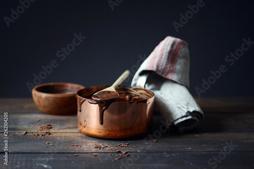 Chocolate sauce on spoon and copper pot photo