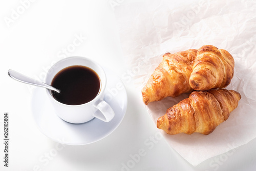 cup of black coffee and croissant on white