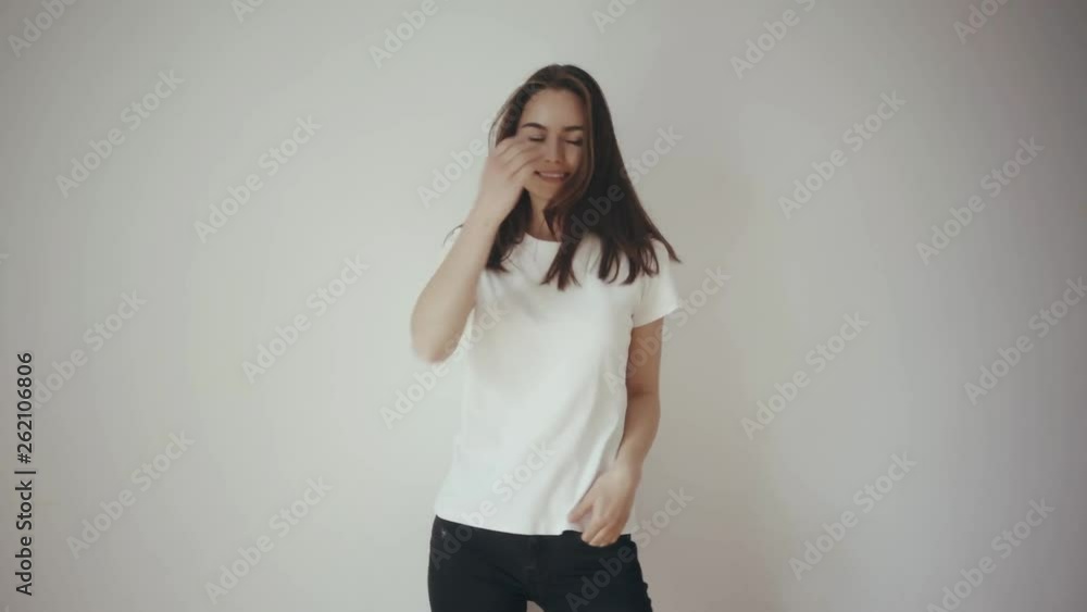 Pretty young hipster girl wearing blank white t-shirt and black jeans, mock-up of blank t-shirt, white isolated background, happy smiling and dancing, laughing and turning around with front and back Pretty young hipster girl wearing blank white t-shirt and black jeans, mock-up of blank t-shirt, white isolated background, happy smiling and dancing, laughing and turning around with front and back