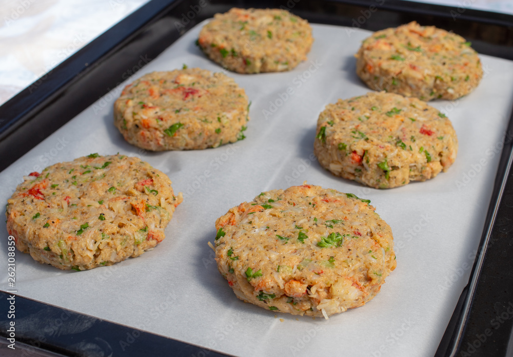 Fototapeta premium Row of best fish cakes raw uncooked on baking tray.