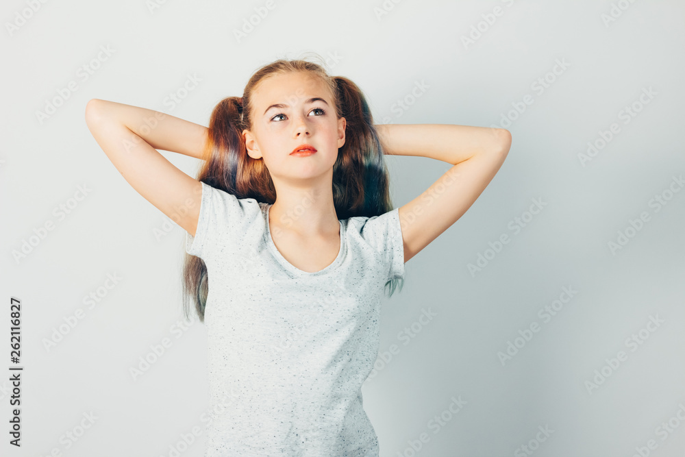 Caucasian girl with hands behind head dreaming. Pensive girl on grey background. Beautiful teenager with multi colored hair. Caucasian girl with hands behind head dreaming. Pensive girl on grey background. Beautiful teenager with multi colored hair.