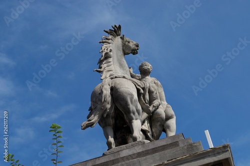 Rear view of statue of horse and man - naked against blue sky