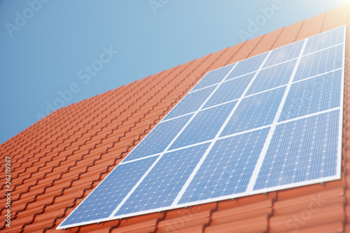 3D illustration solar panels on a red roof of a house. Solar panels with reflection beautiful blue sky. Concept of renewable energy. Ecological, clean energy. Green energy. Photovoltaic Solar cells