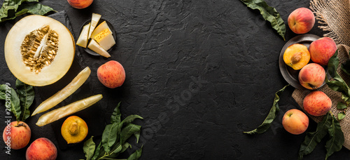 Melon and peaches. Creative layout made of fruits. Colorful fresh fruit on black stone background. Top view, flat lay