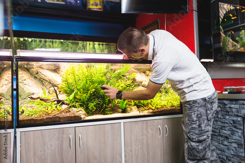 Man cleaning aquarium using magnetic fish tank cleaner. .