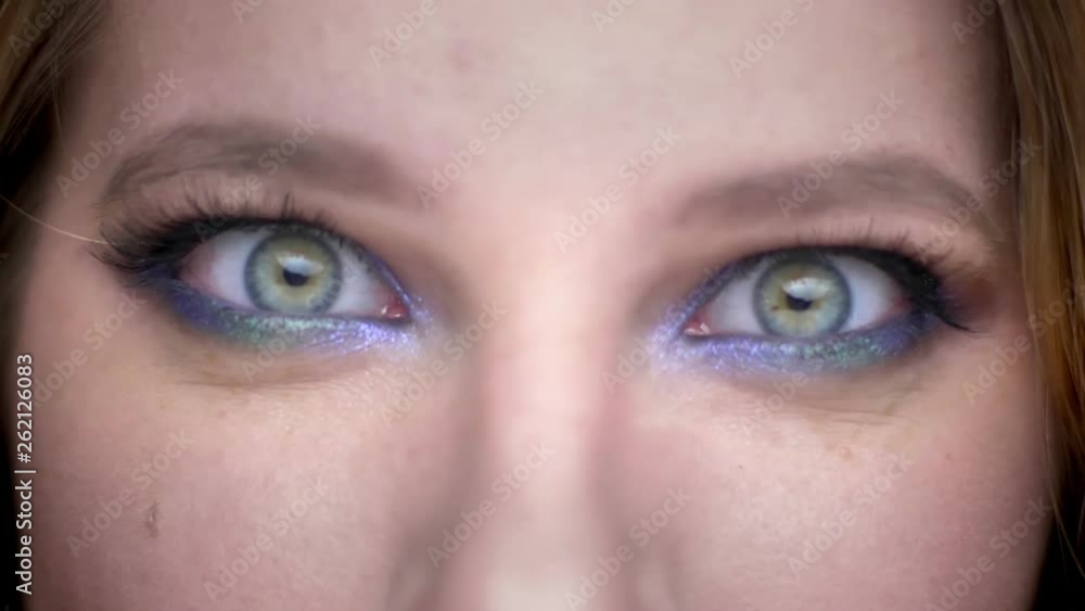 Closeup shoot of young beautiful female face with eyes looking at camera with crazy facial expression with beautiful makeup applied Closeup shoot of young beautiful female face with eyes looking at camera with crazy facial expression with beautiful makeup applied