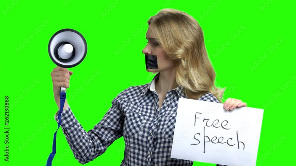 Concept freedom of speech and press. Upset girl with adhesive tape over her mouth trying to shout in a megaphone. Green chroma key background for keying. Concept freedom of speech and press. Upset girl with adhesive tape over her mouth trying to shout in a megaphone. Green chroma key background for keying.