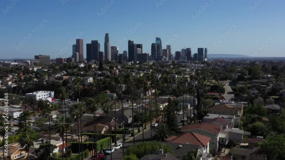 Drone flys over iconic Los Angeles palm tree lined street with the city skyline in the background. Drone flys over iconic Los Angeles palm tree lined street with the city skyline in the background.