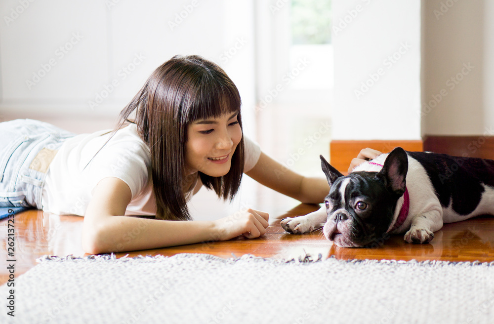 gentle girl in Casual wear with a pug puppy in the bedroom on the floor, bright daylight and light toning